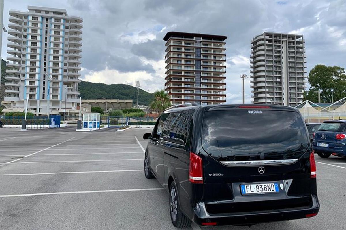 Egy fekete furgon parkolt egy parkolóban, ahol két magas épület volt.