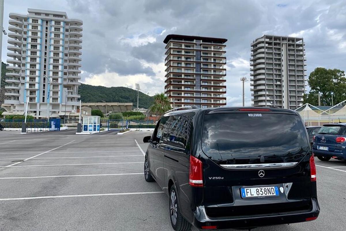 en svart varebil parkert på en parkeringsplass med høye bygninger