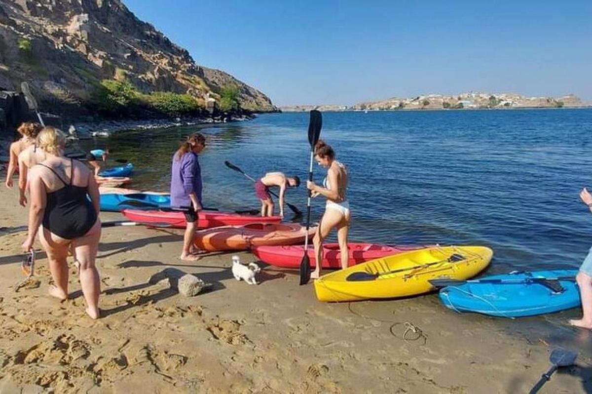 sekumpulan orang berdiri di pantai dengan kayak