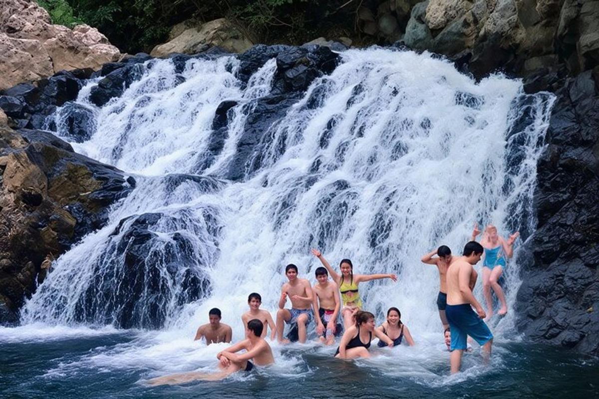 un grup de persones a l'aigua prop d'una cascada