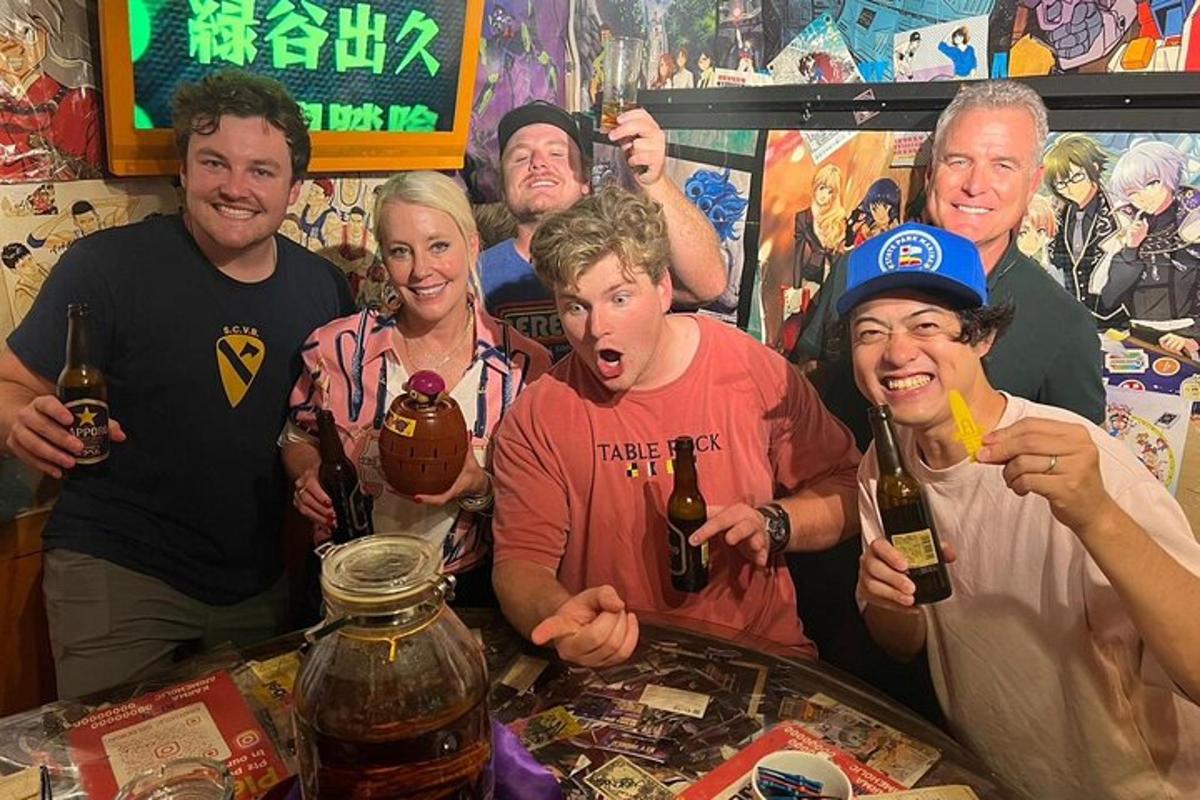 一群人围着桌子站着，桌上放着几瓶啤酒