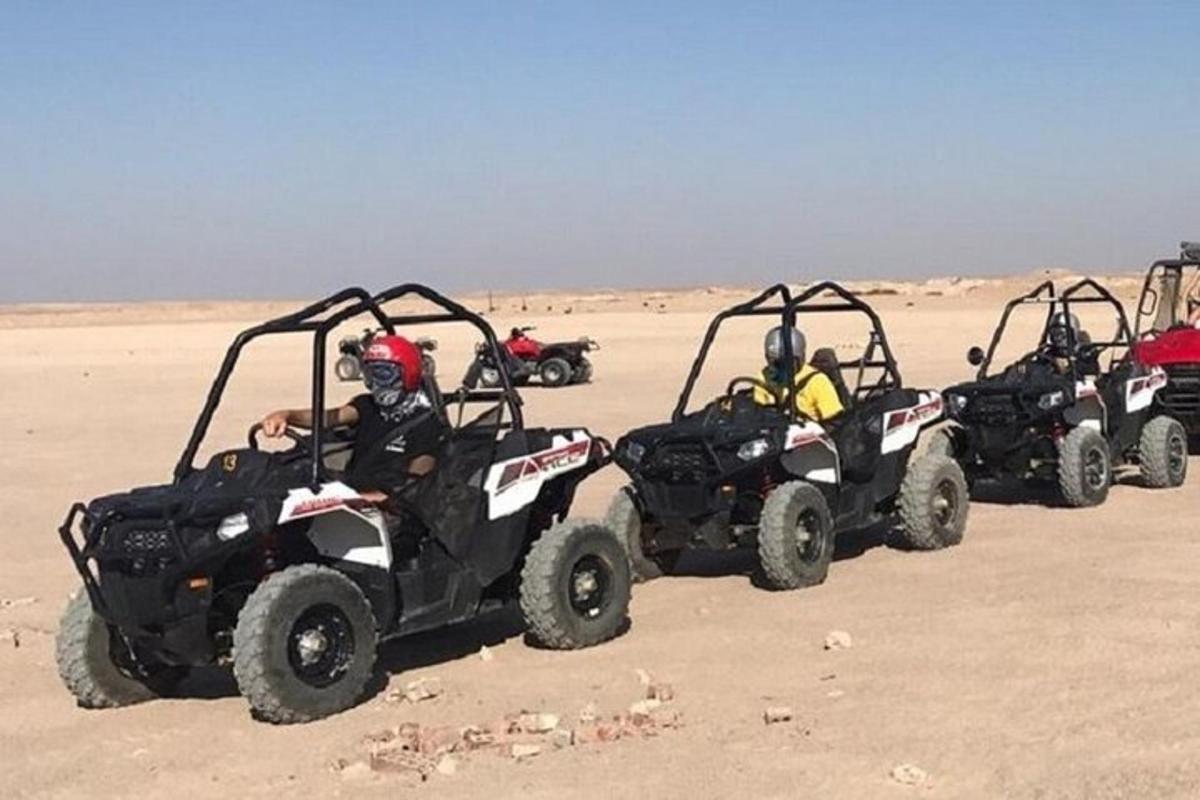 un grup de persones conduint quads al desert