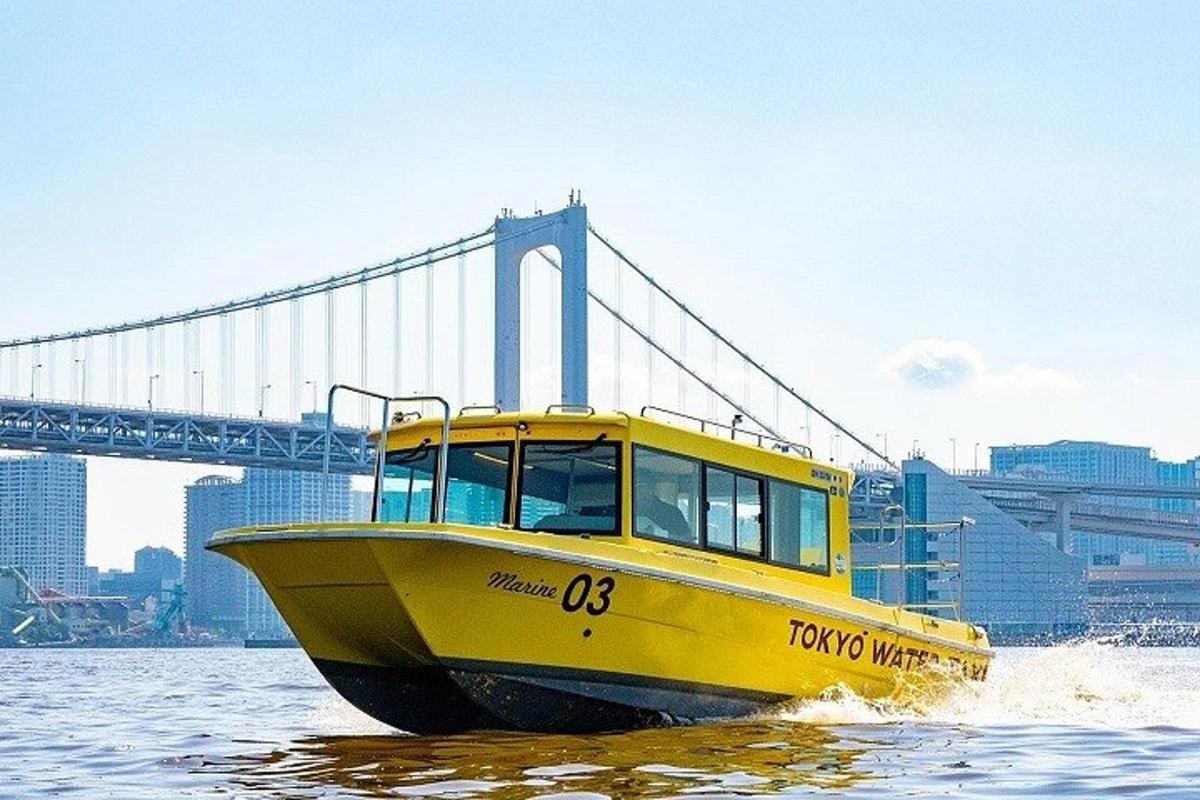 a yellow boat in the water in front of a bridge
