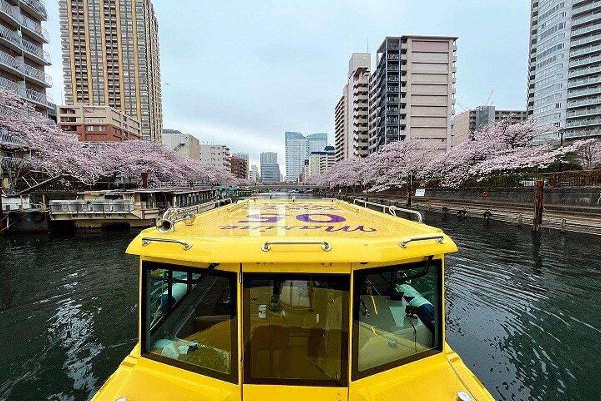 a yellow boat in a river with cherry trees