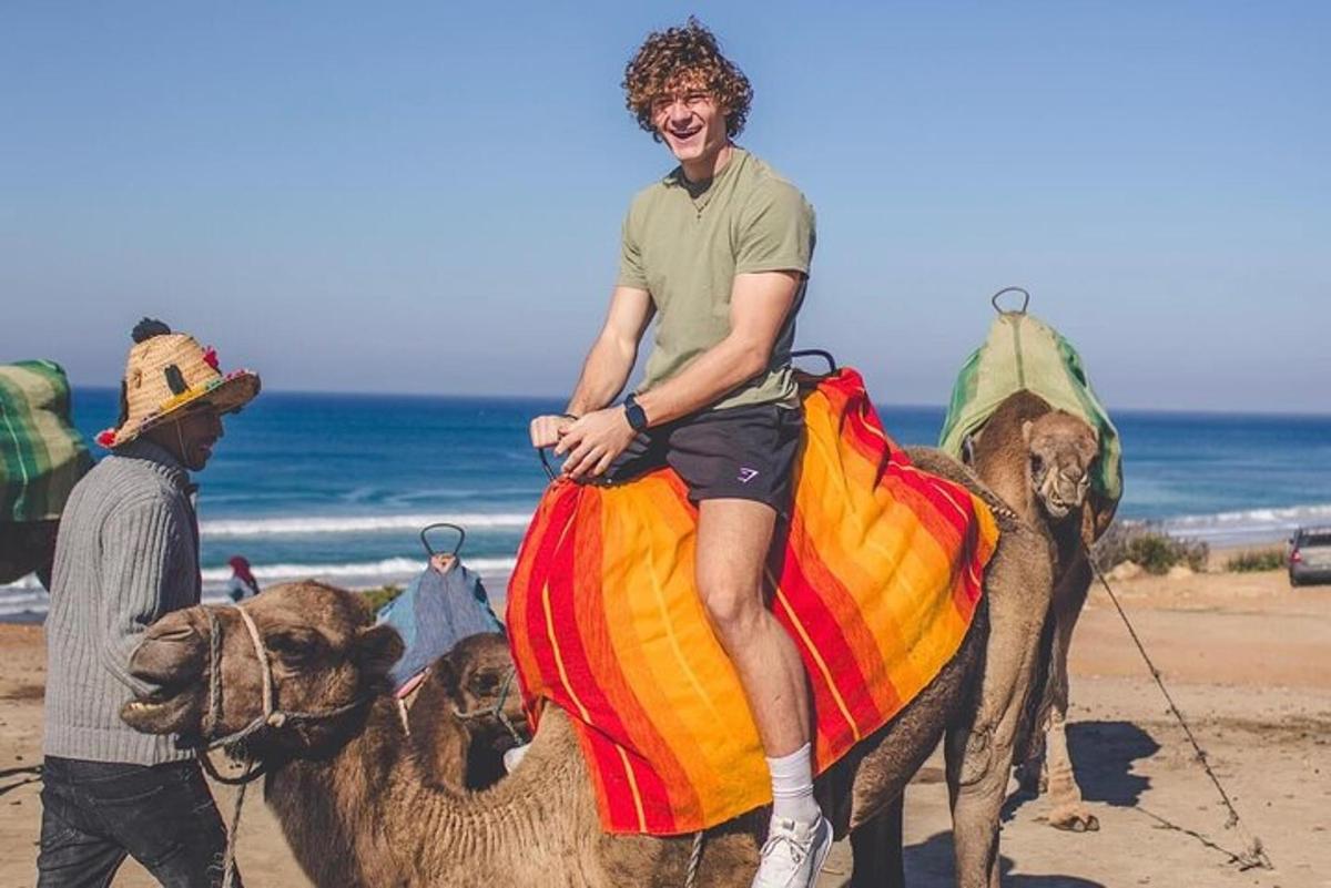 ein Mann, der auf einem Kamel am Strand reitet