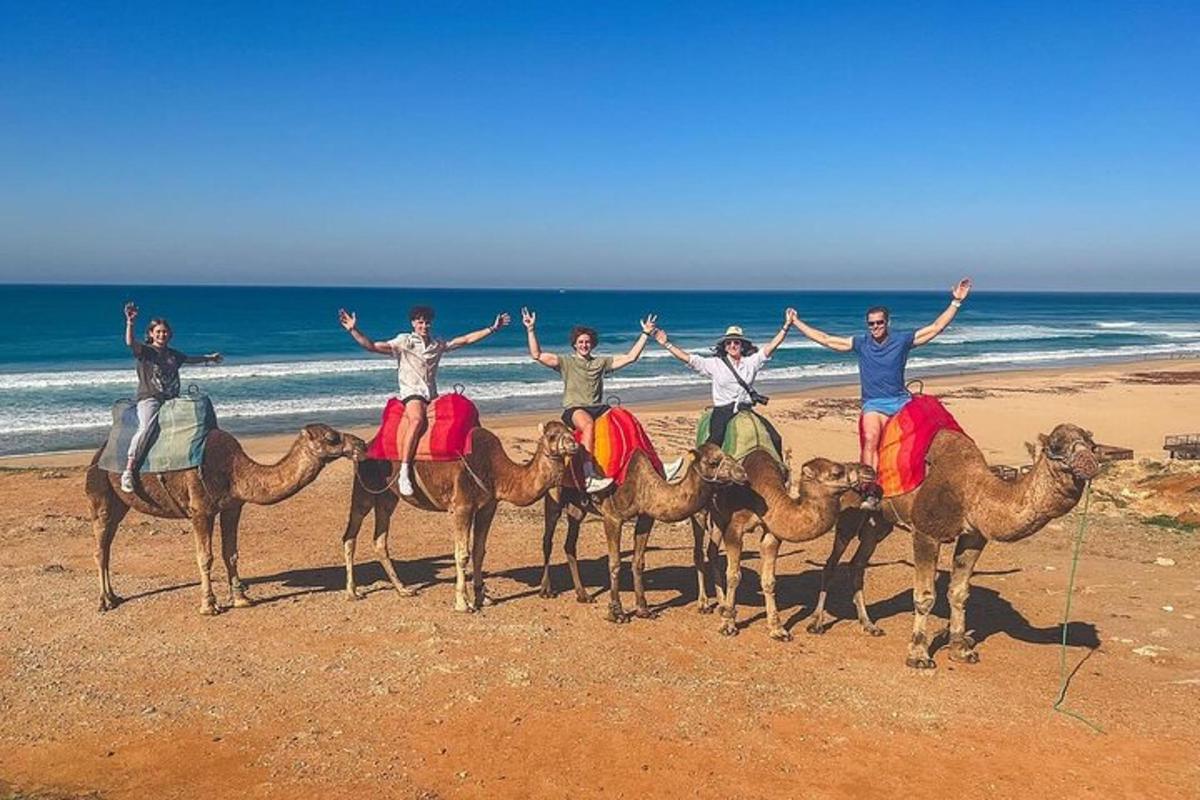 un grupo de personas en camellos en la playa