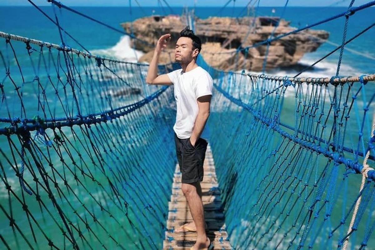 ein Mann steht auf einer Hängebrücke über dem Meer