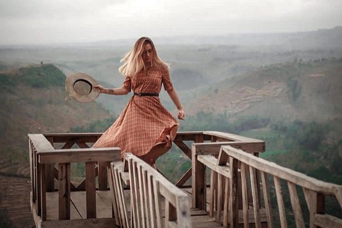 uma mulher está parada na beira de uma montanha