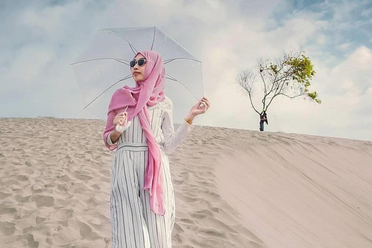eine Frau steht am Strand und hält einen Regenschirm