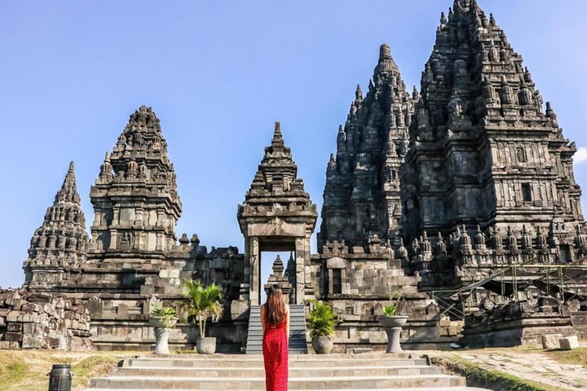 seorang wanita berpakaian merah berdiri di depan kuil