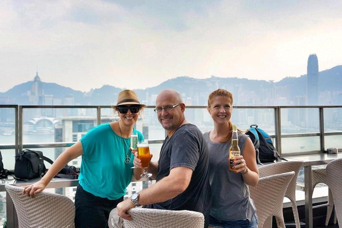 tři lidé pózují pro fotku na balkóně s drinky