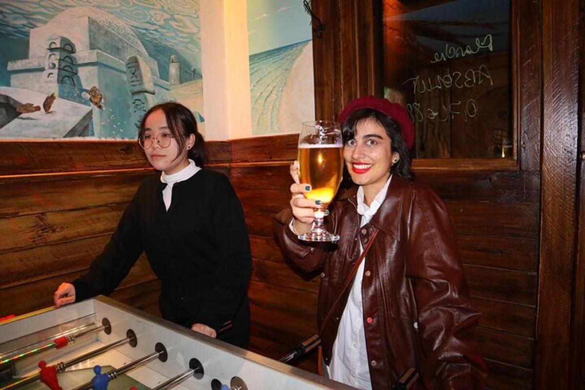 due persone in piedi in un bar con in mano un bicchiere di birra