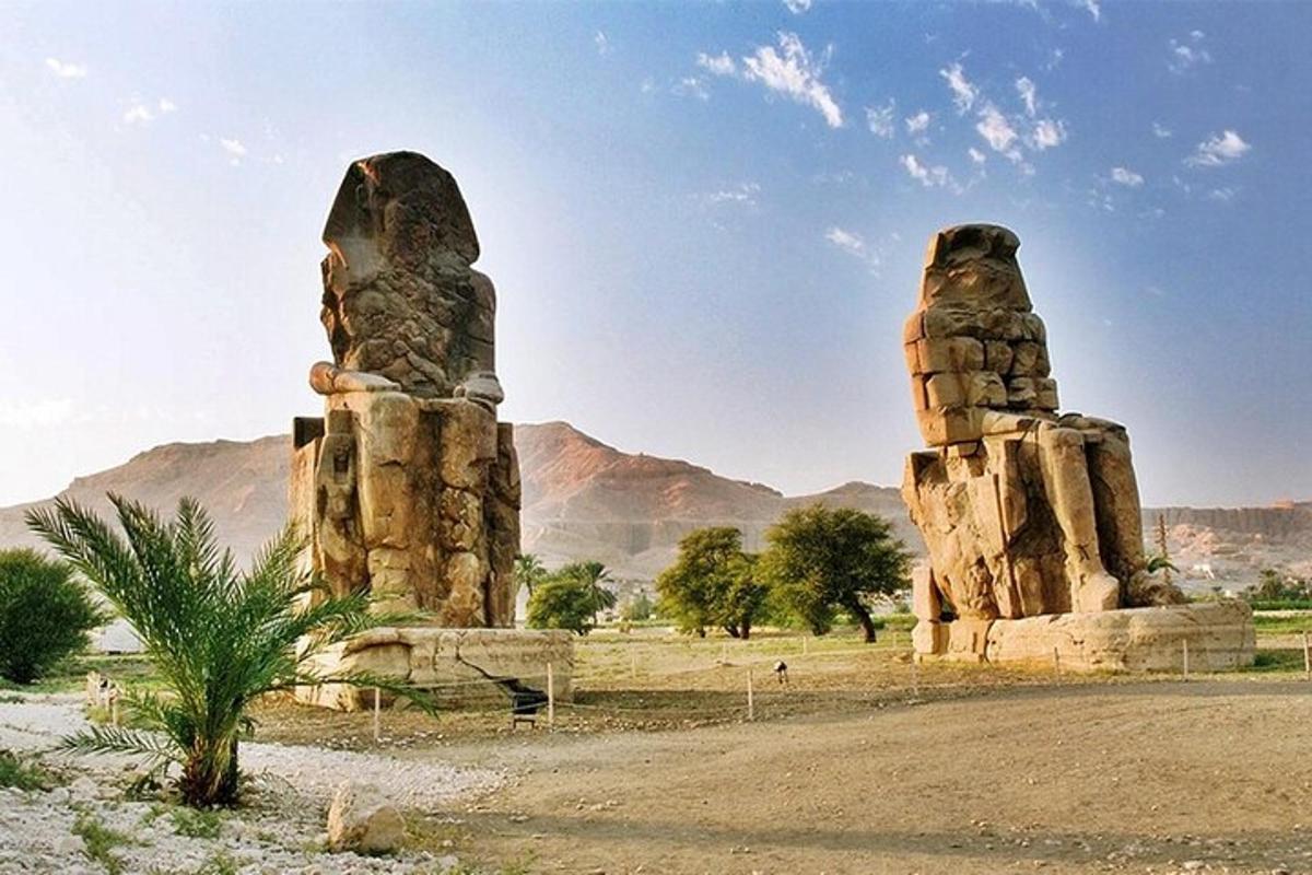Dos estatuas de piedra en un desierto con montañas al fondo