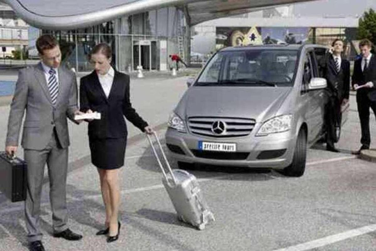 um homem e uma mulher puxando uma mala na frente de um carro