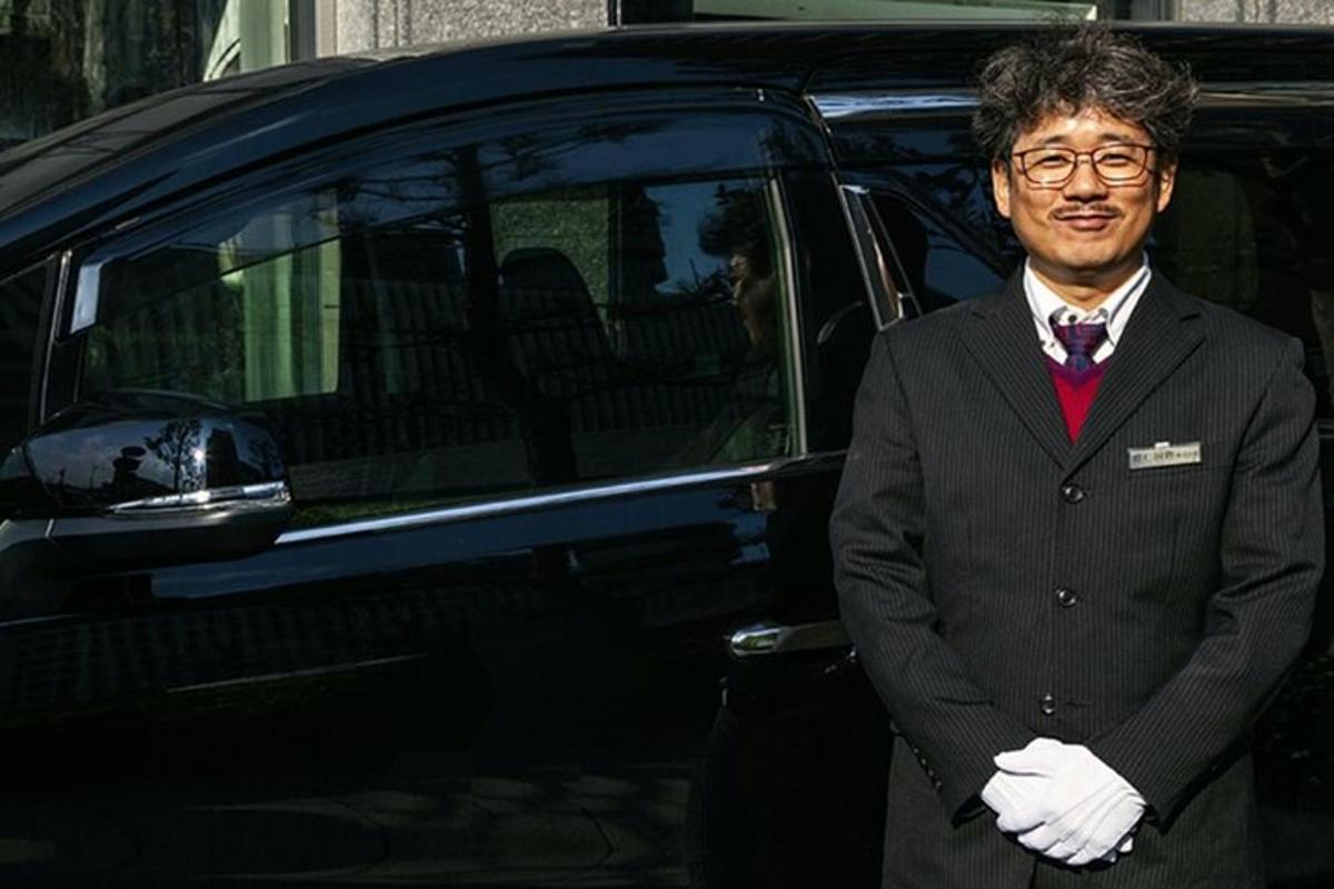 a man in a suit standing in front of a car