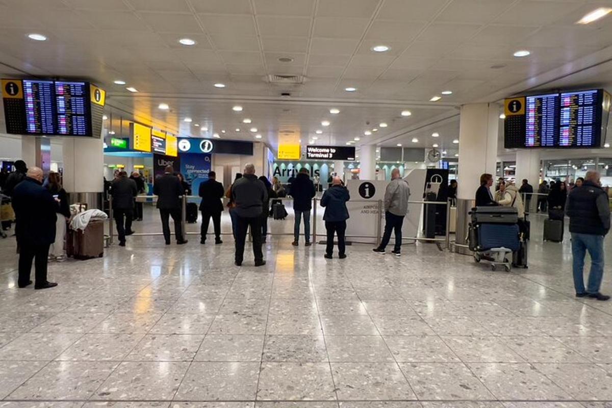 cilvēku grupa, kas pastaigājas pa lidostas termināli