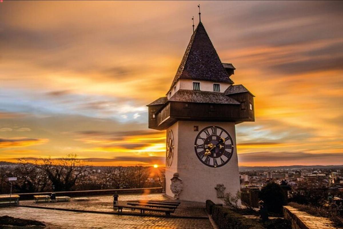 stolp z uro in sončnim zahodom v ozadju