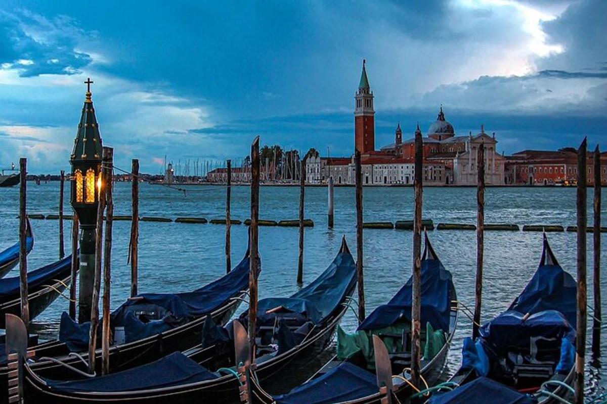 un gruppo di gondole nell'acqua di fronte a una città