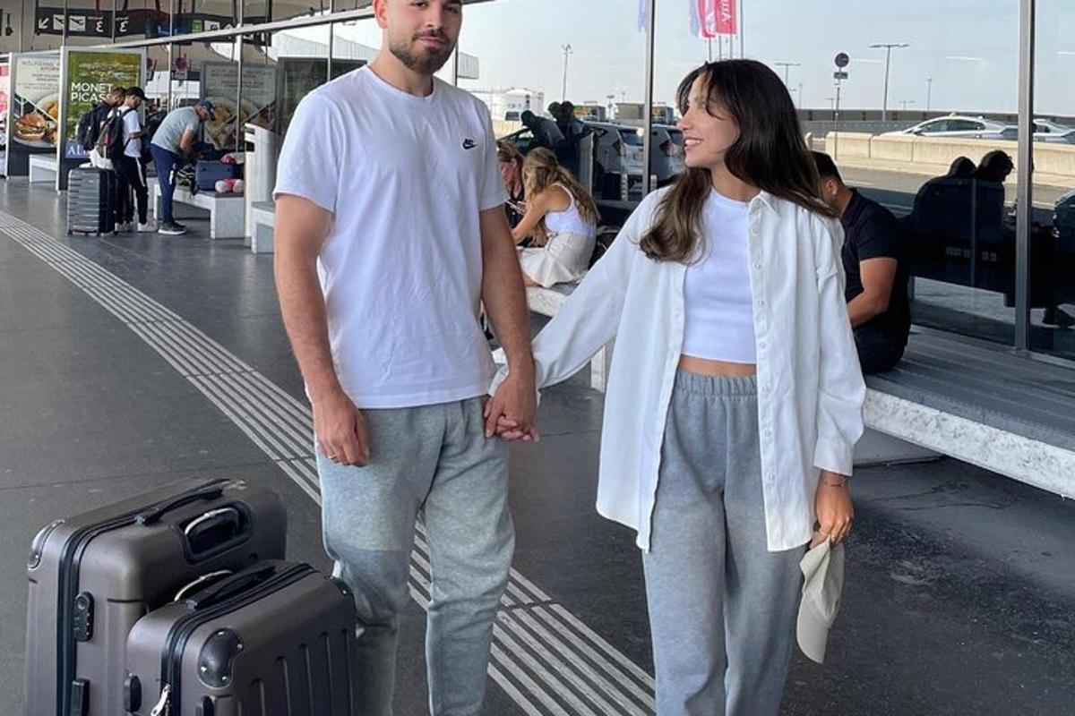 um homem e uma mulher parados em um aeroporto com bagagem
