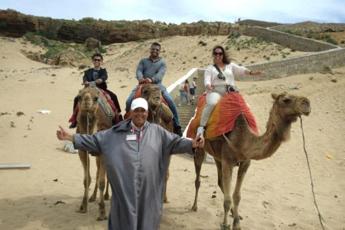 en gruppe mennesker, der rider på kameler på stranden