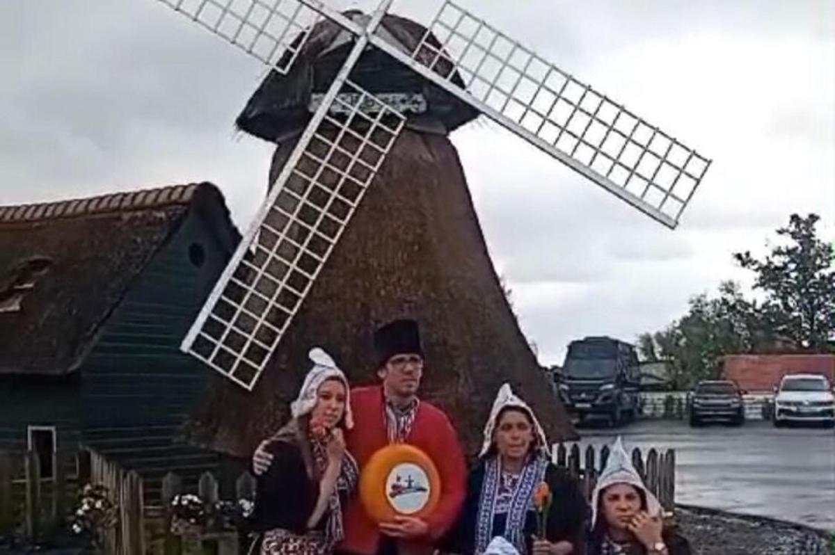 Un grupo de personas de pie frente a un molino de viento.