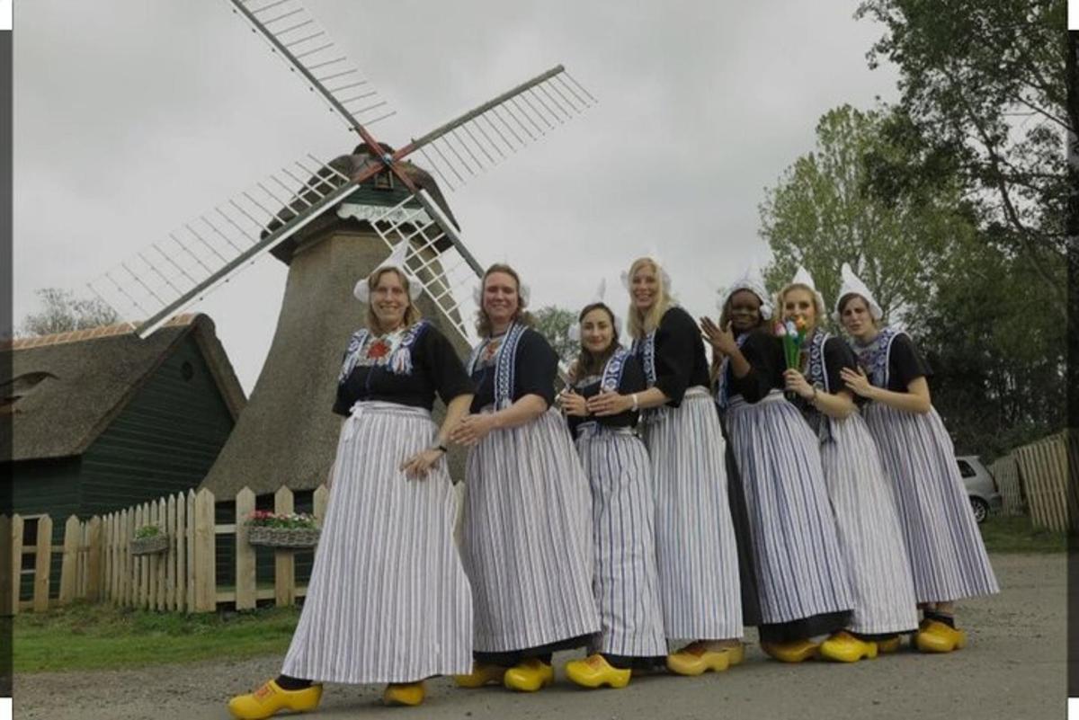 Un grupo de mujeres de pie frente a un molino de viento.