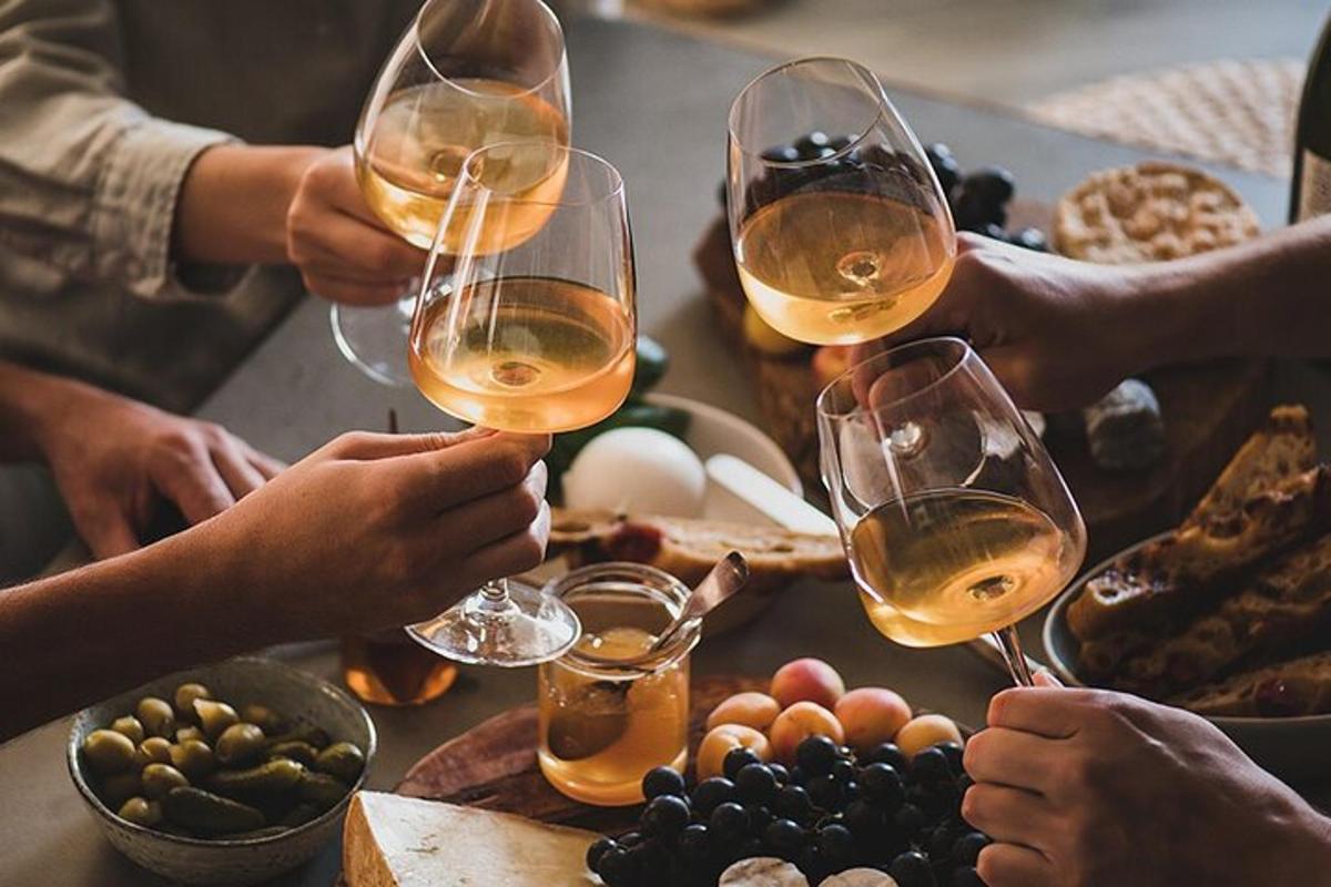 un grup de oameni care beau vin la o masă cu mâncare