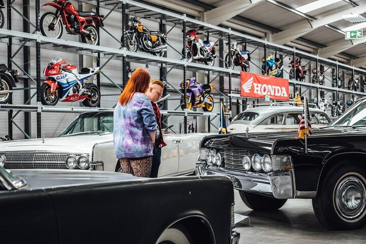two women standing in front of cars in a garage