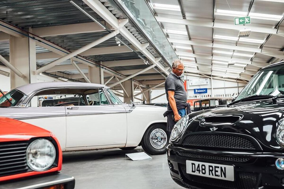 a man standing in a garage looking at cars