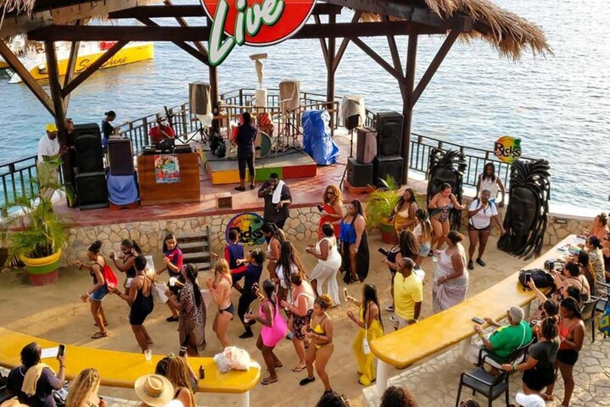 un grup de oameni care dansează la o petrecere lângă apă