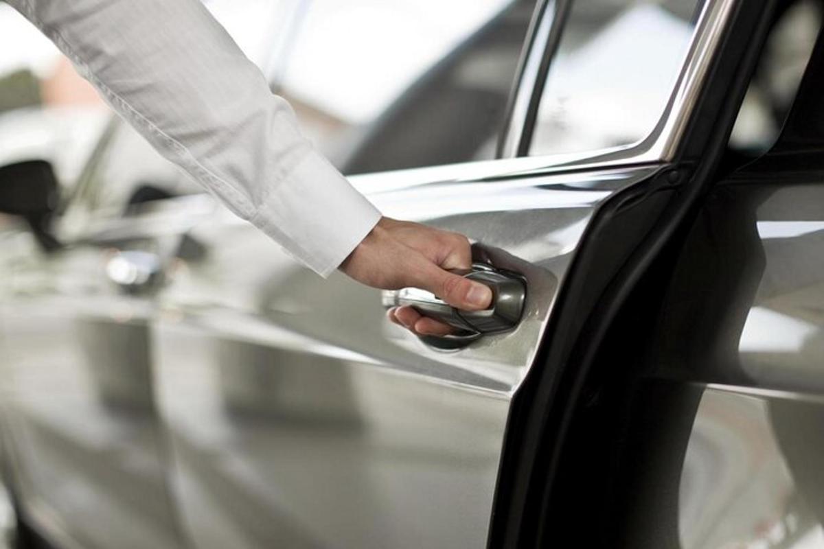 osoba odemykající auto klikou dveří