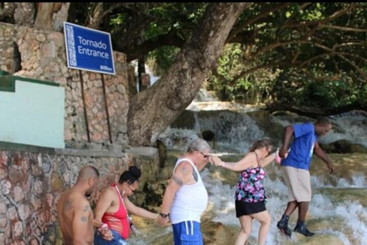 μια ομάδα ανθρώπων που στέκονται μπροστά σε έναν καταρράκτη