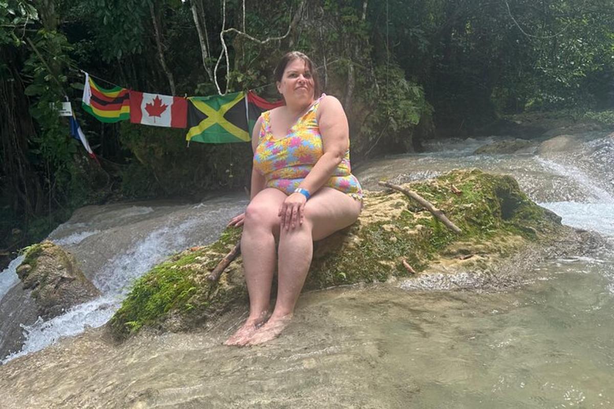 a woman in a bathing suit sitting on a rock in a river