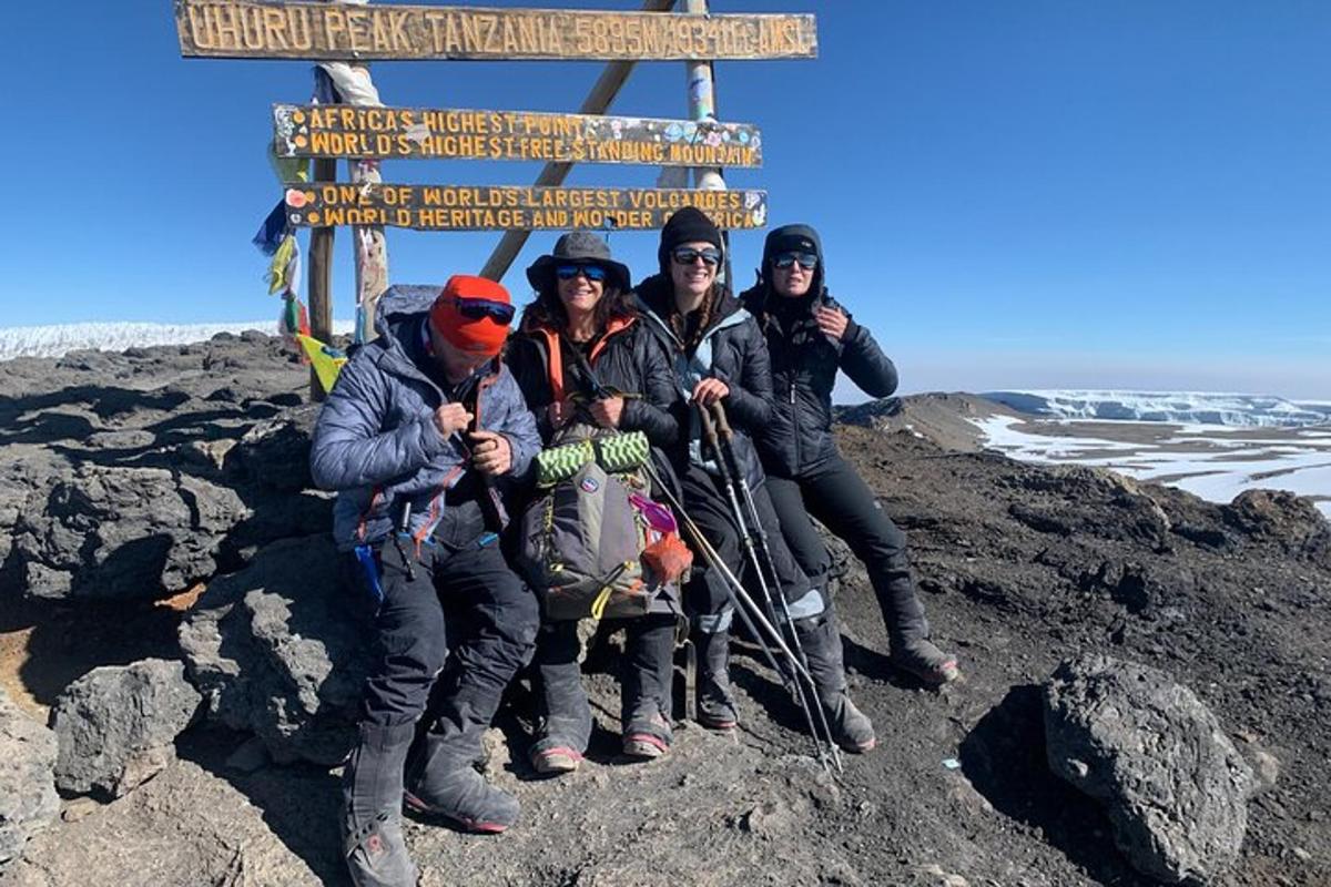um grupo de pessoas em pé ao lado de uma placa em uma montanha