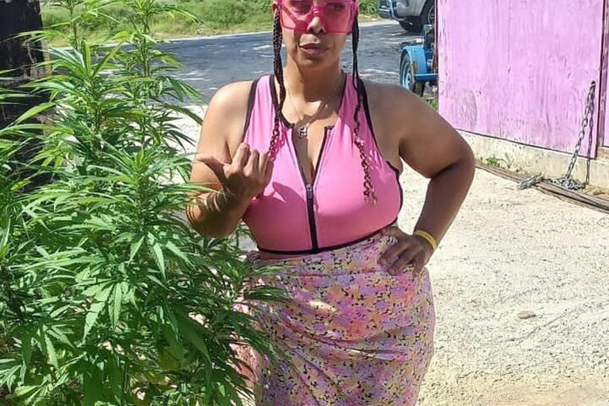 seorang wanita berbaju merah jambu berdiri di sebelah tumbuhan
