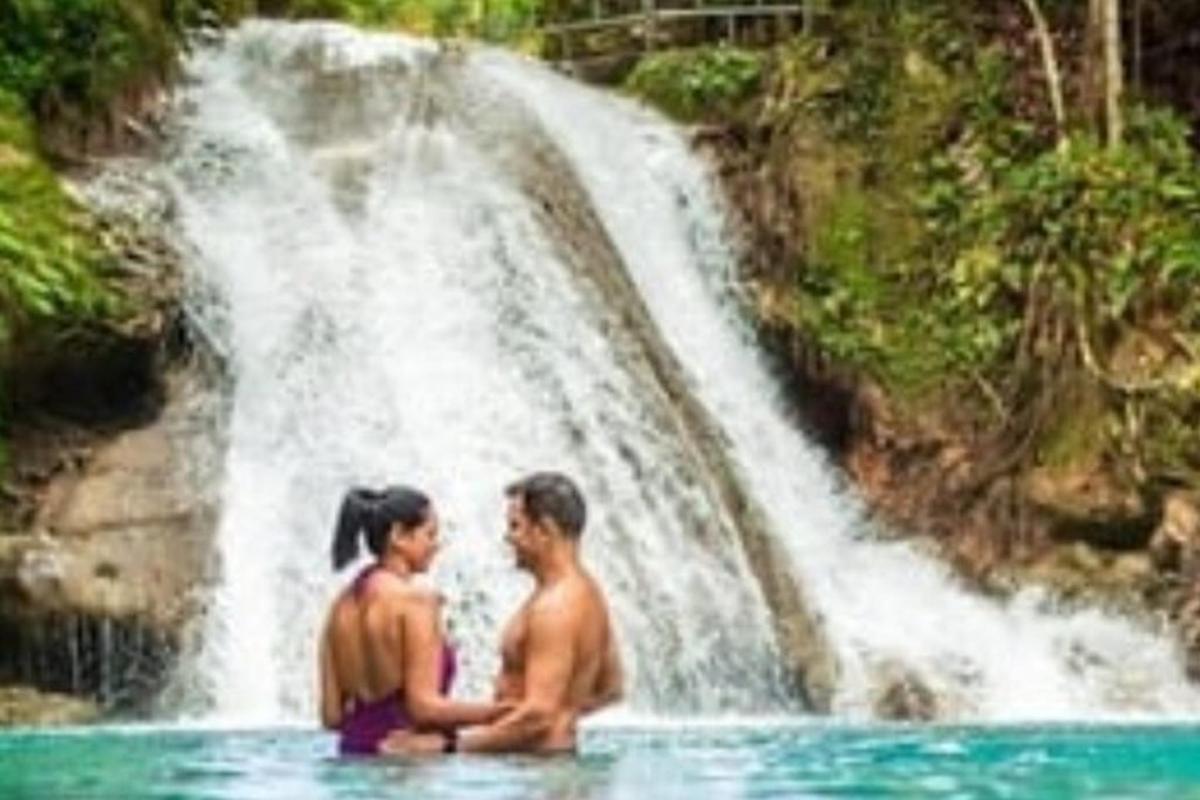 una parella asseguda a l'aigua davant d'una cascada