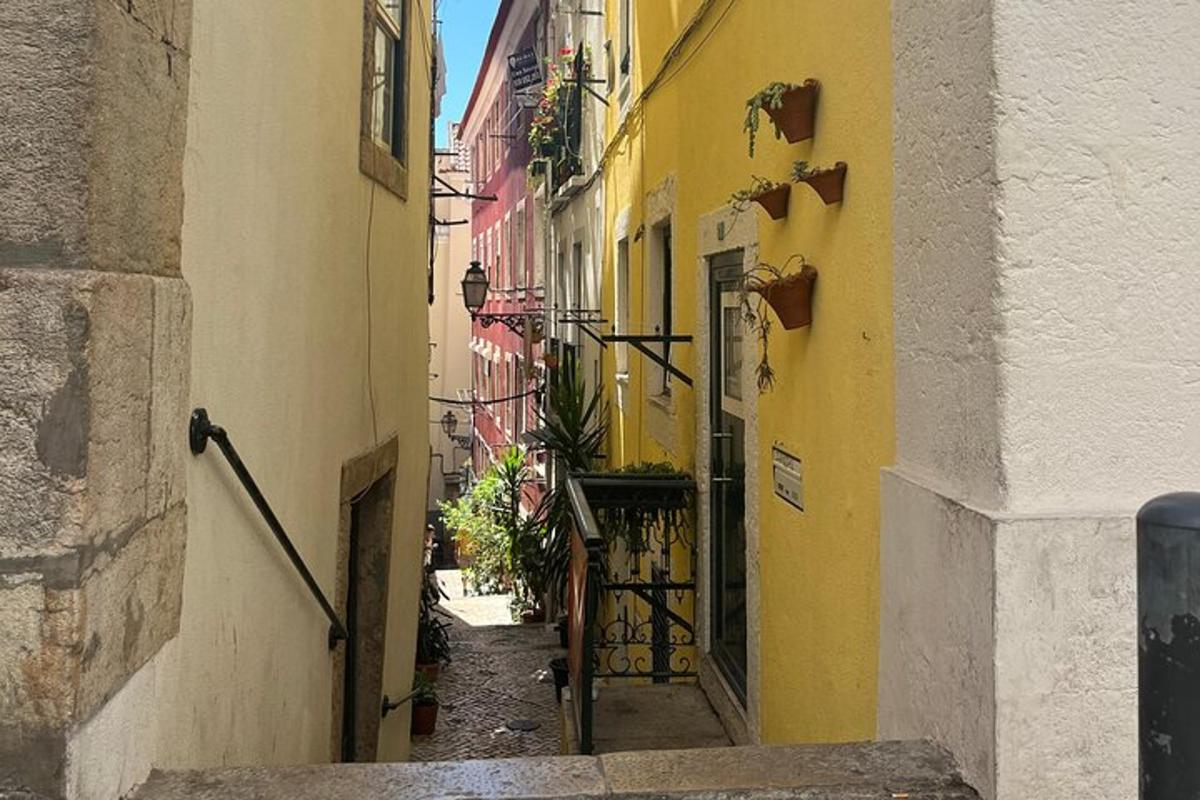 an alley with yellow and white buildings and plants