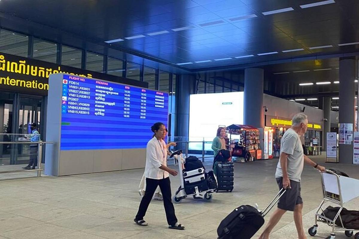 dve osebi, ki se sprehajata po letališču s svojo prtljago