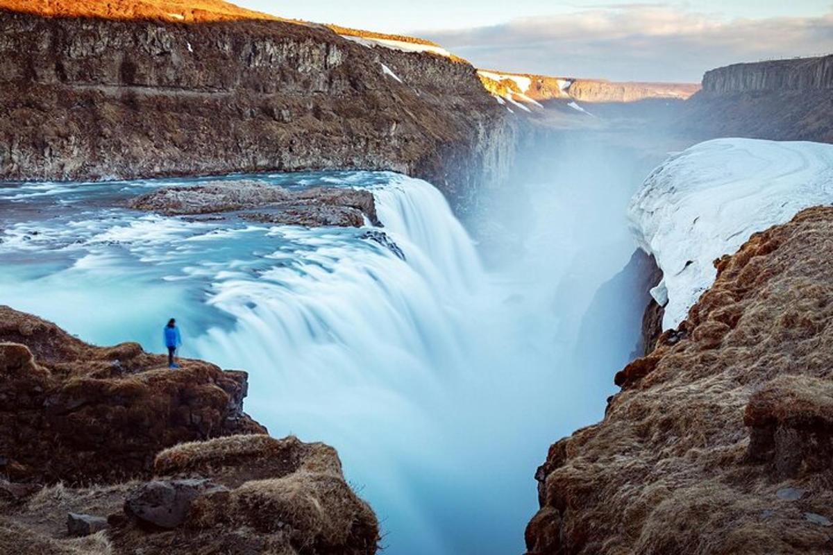 un uomo in piedi su una scogliera accanto a una cascata