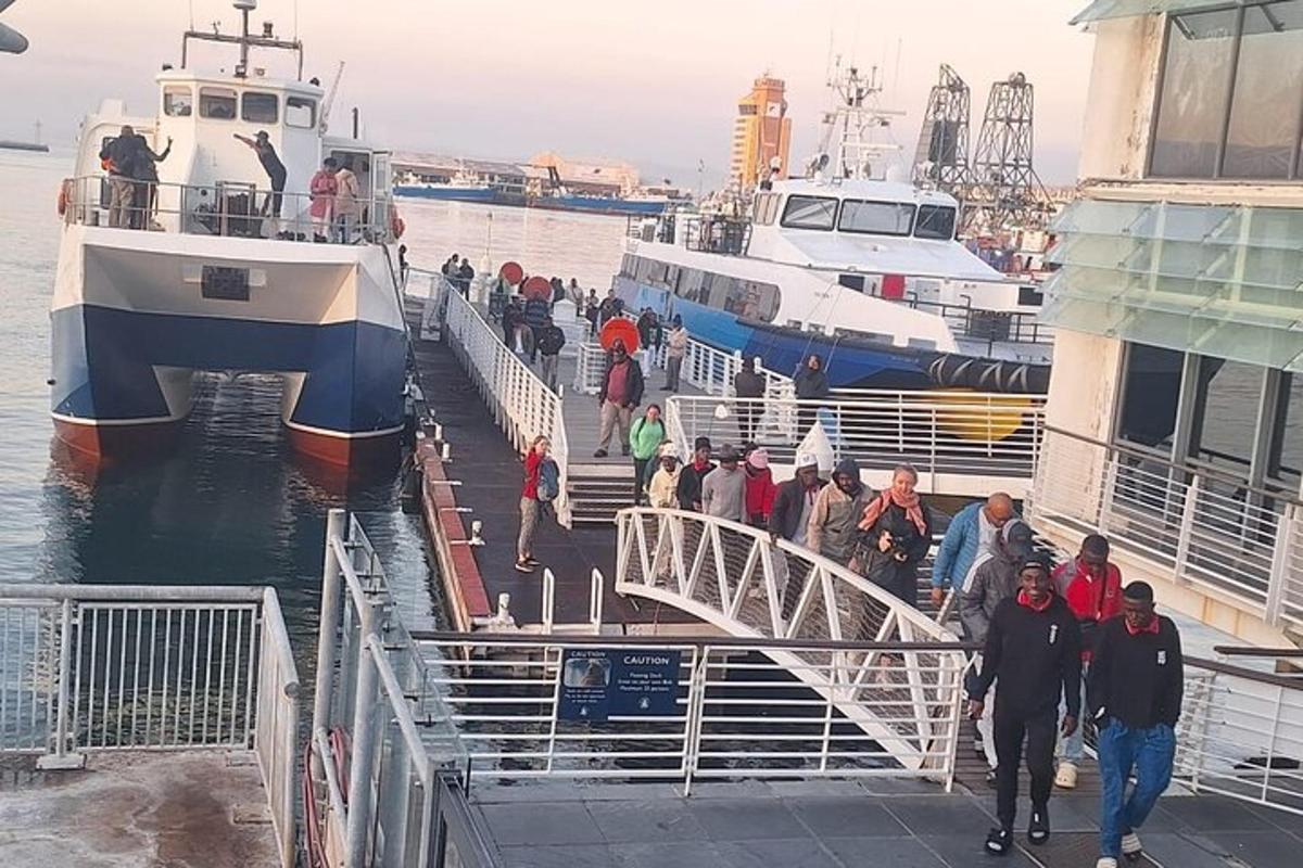 un gruppo di persone che camminano su un molo vicino a due barche