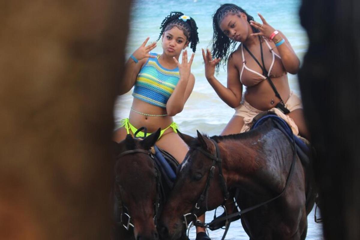 two women in bathing suits riding a horse in the water