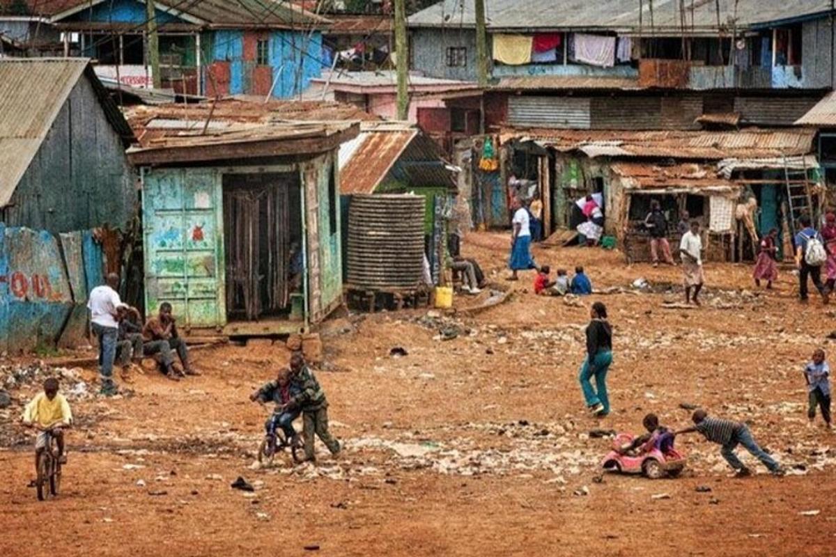 Un grupo de personas en un campo de tierra con edificios.