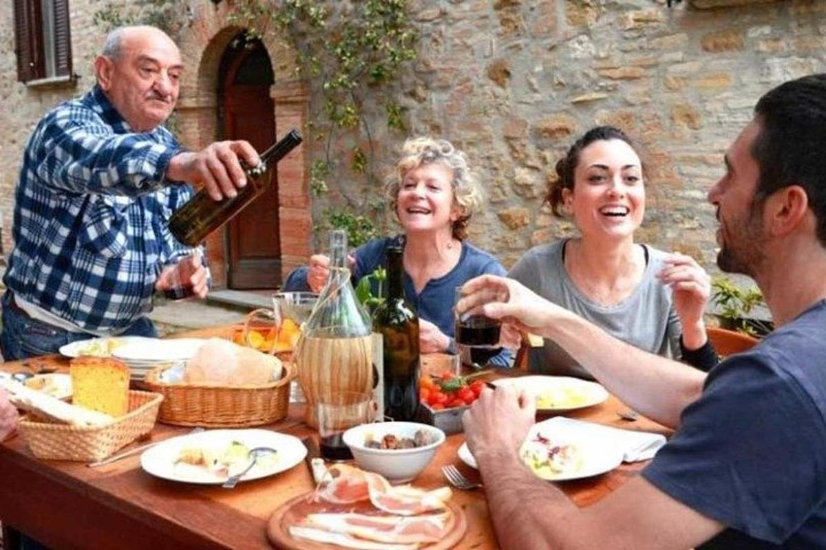 μια ομάδα ανθρώπων που κάθονται γύρω από ένα τραπέζι πίνοντας κρασί