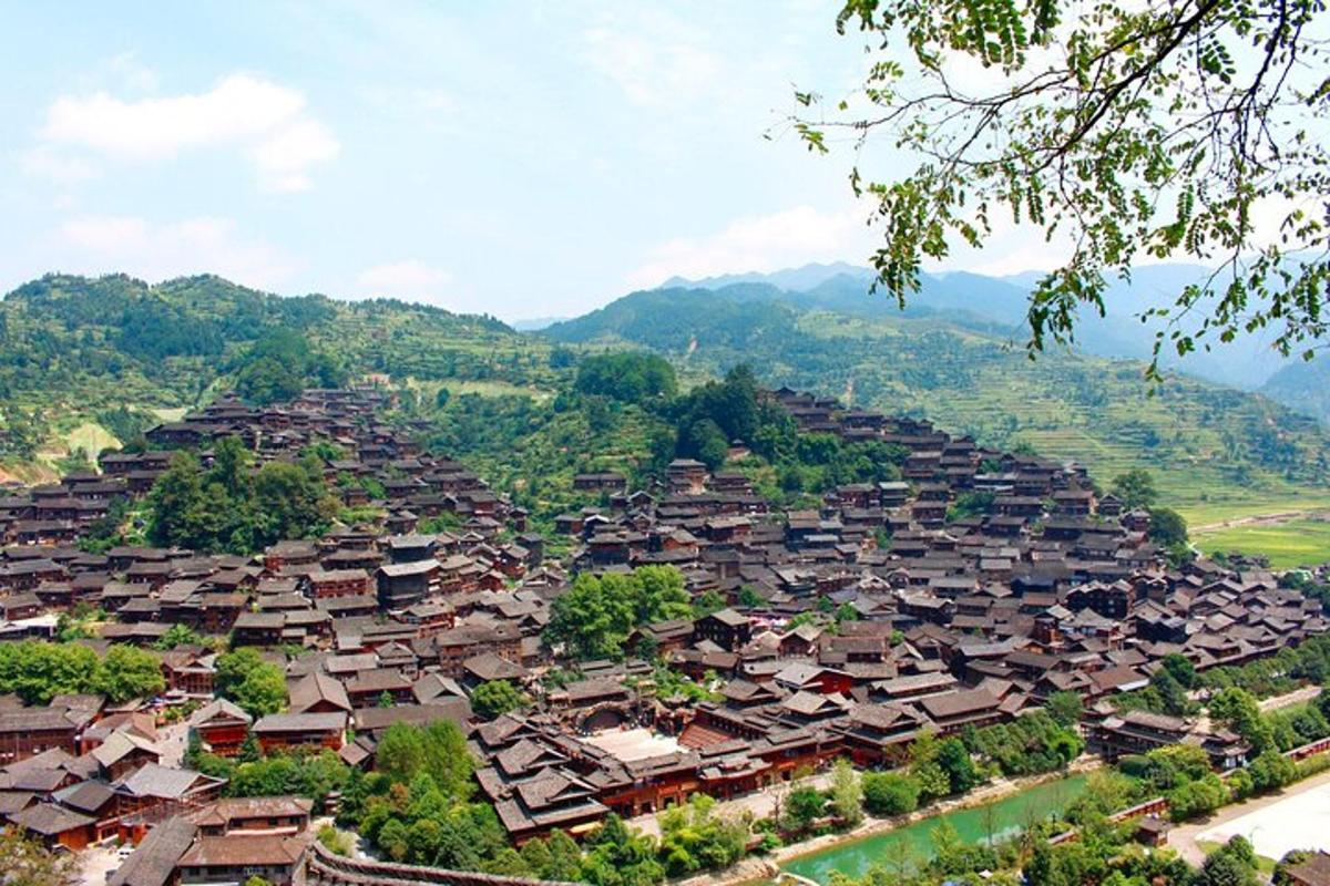 a village on a hill with mountains in the background