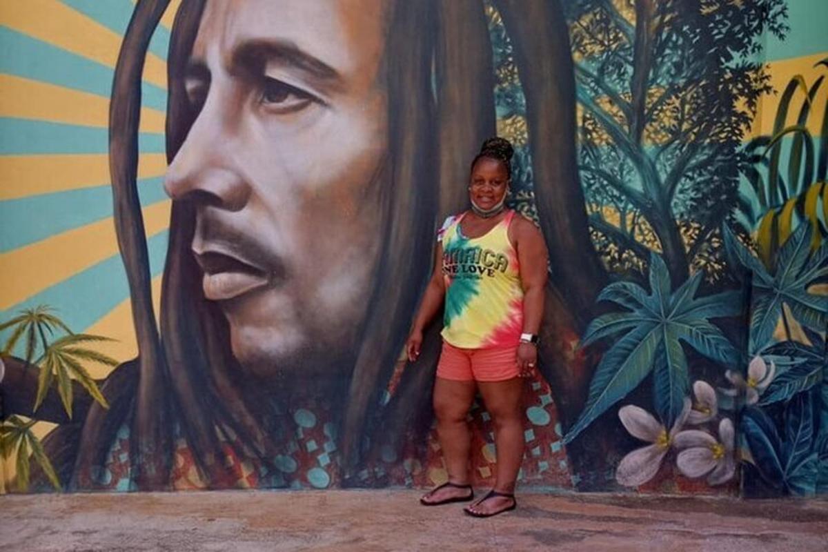 Una mujer parada frente a un mural de un hombre.