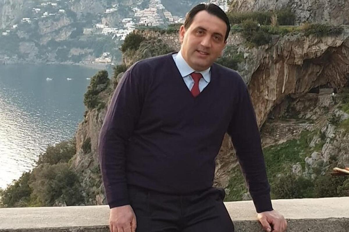 Ein Mann in Anzug und Krawatte steht neben dem Meer