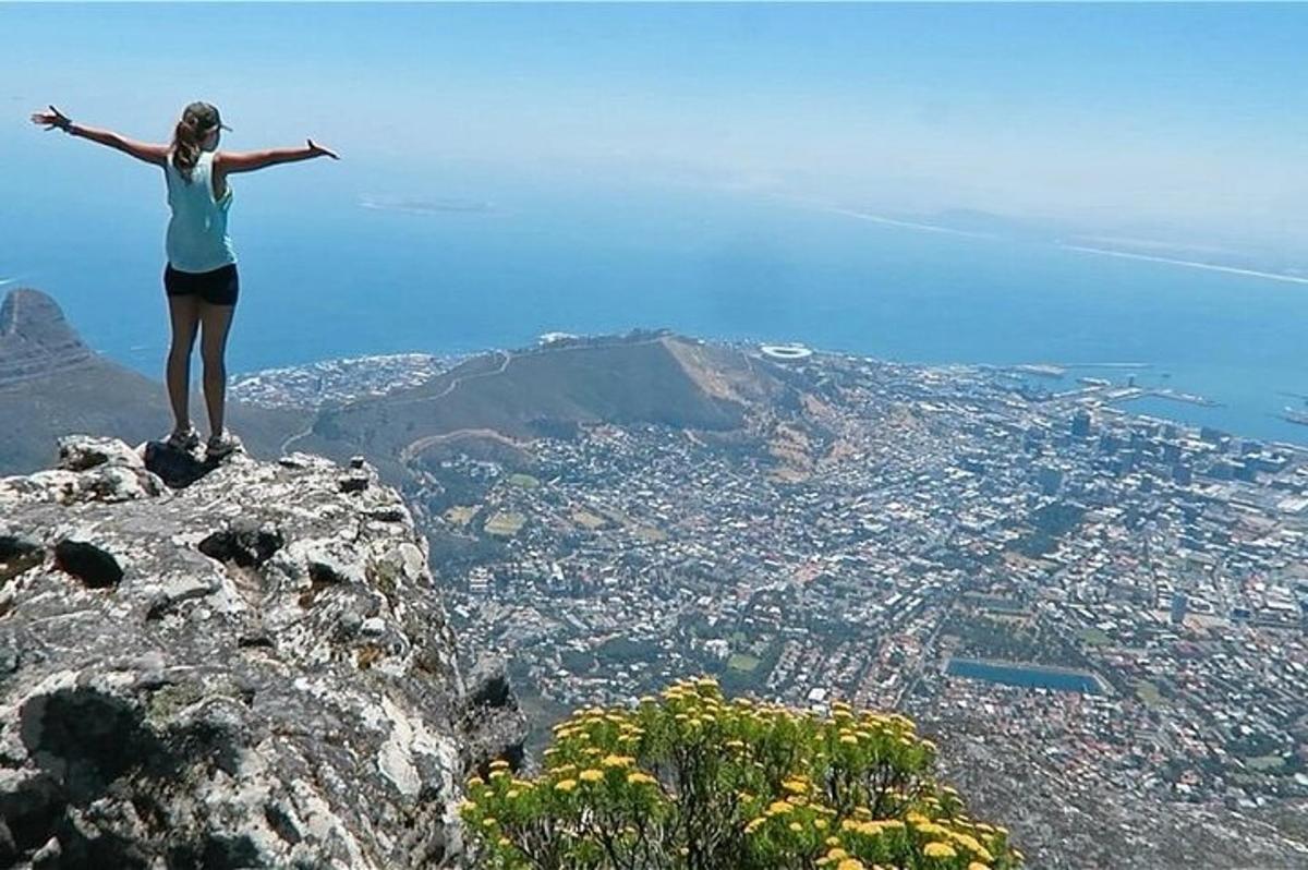 ženska, ki stoji na vrhu gore z iztegnjenimi rokami