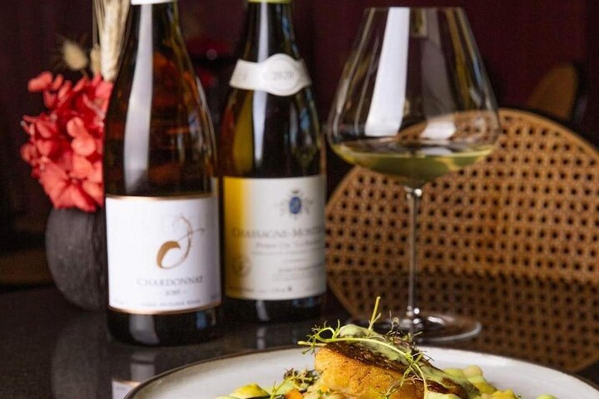 miza z dvema steklenicama vina in krožnikom hrane
