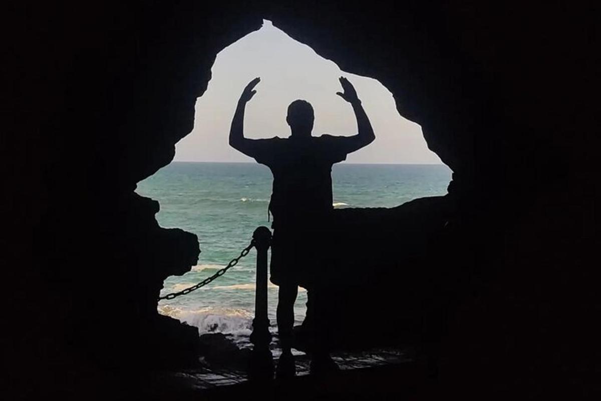 a man standing inside of a cave with his arms in the air