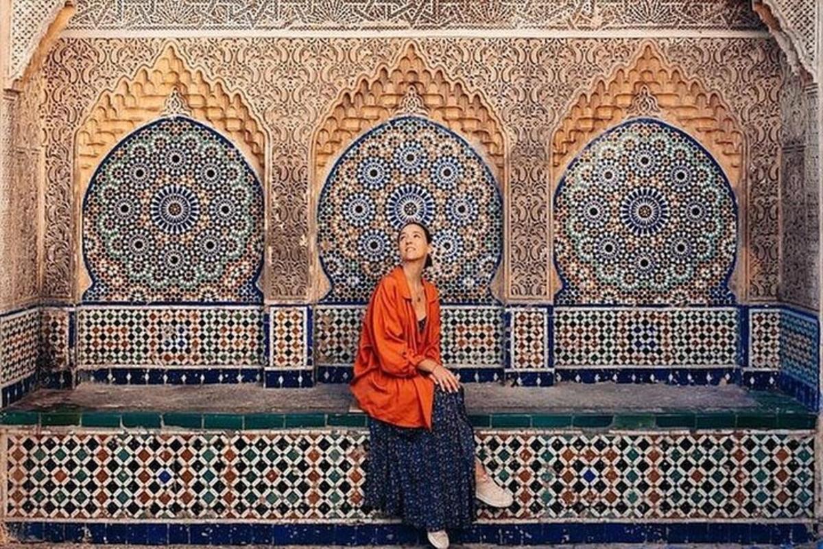 a monk sitting in front of a wall with tiles